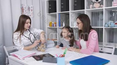 医生给小女孩看如何雾化毛绒玩具。 医生在吸入前安慰小女孩。